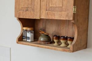 a wooden cabinet with four cups and a pot on a shelf at The Nook - Stylish Homestay - Heart of Frome in Frome +7 photos