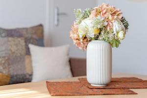 a white vase with a bouquet of flowers on a table at Kajüte Nr 2 in Neue Tiefe Fehmarn