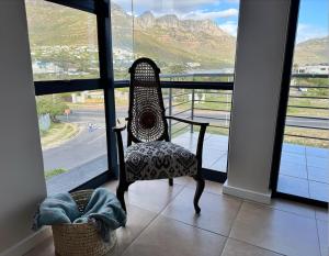 a chair sitting in front of a window with a view at Ocean facing apartment in Hout Bay