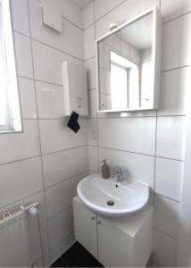 une salle de bain blanche avec un lavabo et un miroir dans l'établissement Gemütliche Appartement 1 - mit Küche und Bad zur Eigennutzung -Schuster Homes-, à Vechelde
