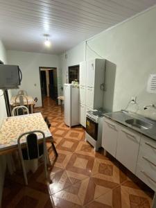 uma cozinha com eletrodomésticos brancos e uma mesa e uma mesa e cadeiras em Pouso das Folhas em Tiradentes