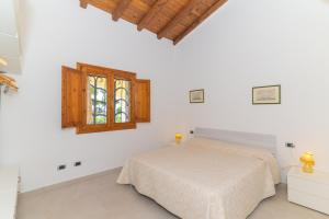 a white bedroom with a bed and a window at San Teodoro Villa Nina Costa Caddu in San Teodoro