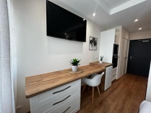 a kitchen with a desk with a television on the wall at La Suite Faïence, chic et calme in Panazol
