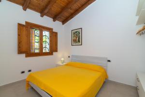 a bedroom with a yellow bed and a window at San Teodoro Villa Ambra Costa Caddu in San Teodoro