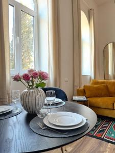 a dining room table with a vase of flowers on it at Love&Loft central park with private garden in Baia Mare