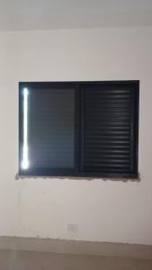 a window with blinds on a white wall at Casa da família in Ubatuba