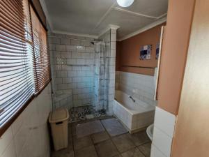 Un baño con ducha, inodoro y bañera. en Lullaby Leaves Guesthouse, en Lichtenburg