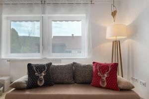 a couch with pillows on it with two windows at Ferienwohnung am Schwellenweiher in Feldberg