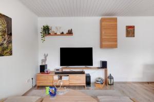 a living room with a flat screen tv on a white wall at Ferienwohnung am Schwellenweiher in Feldberg
