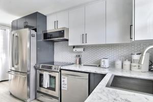 a kitchen with white cabinets and stainless steel appliances at Quebec city Downtown River Sidewalk 2 Free Parking in Quebec City +44 photos