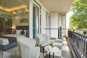 a bedroom with a bed and chairs on a balcony at Saltstayz Premier - Arjun Marg in Gurgaon