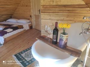 a room with a tub with a bottle of wine and glasses at Noapte de Poveste in Piatra Fantanele