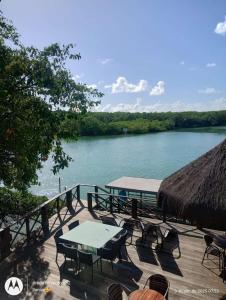 a deck with tables and chairs next to a river at POUSADA Dunas de Marape - Alagoas in Jequia da Praia