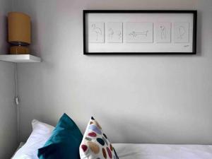 a picture hanging on a wall above a bed with pillows at Cosy Georgian Cottage - Parking - Central Frome in Frome