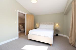 a bedroom with a white bed and a bathroom at Ground Floor Barn with Hot Tub, Dog Friendly, Sleeps up to 8 close to Monmouth, Ross on Wye, Hay on Wye and Hereford! in Broad Oak