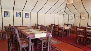 a dining room with tables and chairs in a tent at Camel Experience Camp in Merzouga