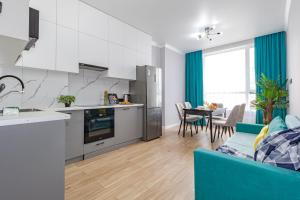 a kitchen and living room with a couch and a table at Apartment Family Home in Astana