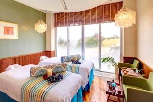 two beds in a room with a window at ANA InterContinental Manza Beach Resort by IHG in Onna