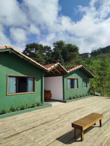 a green house with a bench on a wooden deck at Pousada Verde Serena SFX in São Francisco Xavier