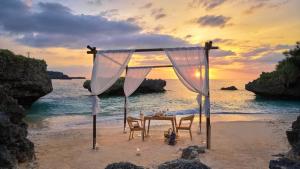 a table and chairs on the beach at sunset at ANA InterContinental Manza Beach Resort by IHG in Onna