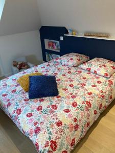 アヴランシュにあるJolie Maison avec piscine, proche Mt St Michelの花柄のキルトと枕が付いたベッド