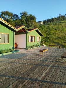 a deck with two green buildings and two benches at Pousada Verde Serena SFX in São Francisco Xavier +25 photos