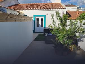 a white house with a blue door and a yard at My home in Cercal