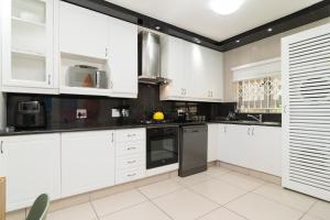 a kitchen with white cabinets and black appliances at La Mustique 4 in Ballito