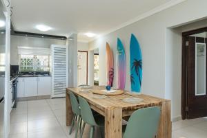 a dining room with a wooden table and surfboards on the wall at La Mustique 4 in Ballito
