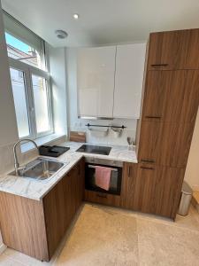 eine Küche mit Holzschränken und Spüle und einem Fenster in der Unterkunft Luxueux logement proche gare et centre ville in Tourcoing