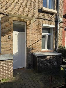 ein Backsteinhaus mit einer weißen Tür und zwei Fenstern in der Unterkunft Luxueux logement proche gare et centre ville in Tourcoing