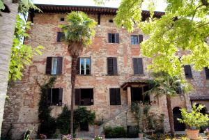 un viejo edificio de ladrillo con una palmera delante de él en Residenza d'Epoca Il Cassero, en Lucignano