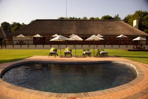 a swimming pool with chairs and umbrellas in front of a building at Ingaadi in Pretoria