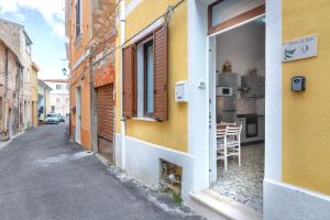 an alley with a yellow building and a table in a kitchen at Domus De Mirto in Sennori