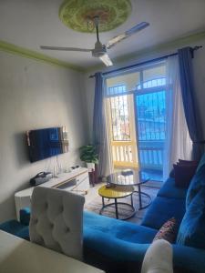 a living room with a blue couch and a tv at The Blue Apartment Sparki in Mombasa