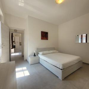 a white bedroom with a bed and a hallway at La Casetta del 26 B&B in Corsico