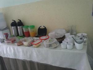 a table with food and drinks and cups on it at Pousada Cariri in Juazeiro do Norte