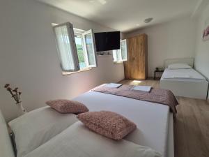a bedroom with two beds and a flat screen tv at Apartmani Niko in Neum