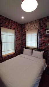 a bedroom with a large white bed in a brick wall at โอรีสอร์ต Oresort in Ban Chua Phloeng