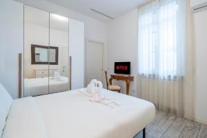 Un dormitorio blanco con una cama blanca y un espejo. en Duomo 15' - Suite 5' from Station with Wifi and A-C, en Milán