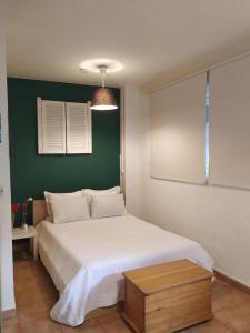 a bedroom with a white bed and a green wall at Art & Books Guesthouse Alexandroupoli in Alexandroupoli