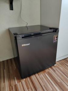 een zwarte koelkast bovenop een houten vloer bij Reds Roomstay Pantai Penarik 4 in Pulau Che Selamah