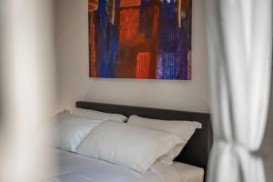 a bed with white pillows and a painting on the wall at The Tower Glimpse in Florence