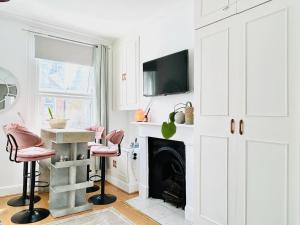 a living room with a fireplace and pink chairs at Apollo Hammersmith Studio in London +15 photos