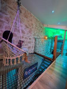 a person sitting in a hammock in a room with a brick wall at Maison Insolite avec Spa Privatif in Monbalen +18 photos
