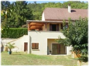 Una gran casa blanca con un patio y un árbol. en Candéjac, en Daglan