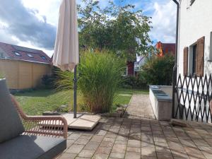 a patio with an umbrella and a chair and a bench at Familienfreundliche Fewo mit Garten in Cadolzburg