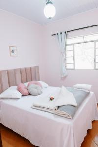 a white bed with pink and blue pillows on it at Casa com piscina próxima a pontos turísticos in São Lourenço +90 photos