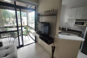 a kitchen with a view of a living room at Riviera Dreams: Piscina, Sauna e muito mais! in Bertioga