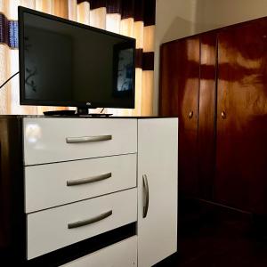 una TV seduta sopra un comò bianco di habitación doble, cama queen, terraza y plantas a Cochabamba